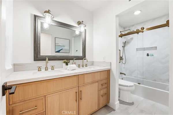 a bathroom with a double vanity sink toilet mirror and shower