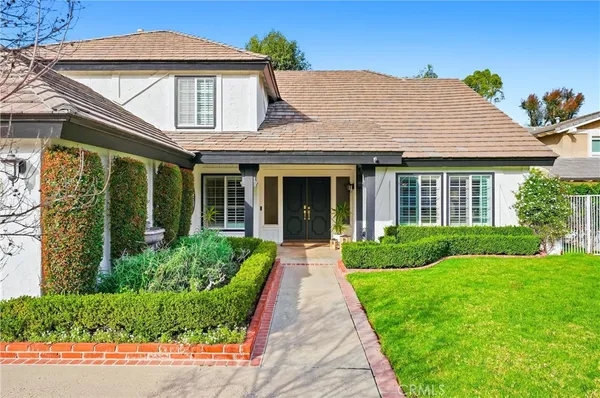 a front view of a house with a yard and potted plants