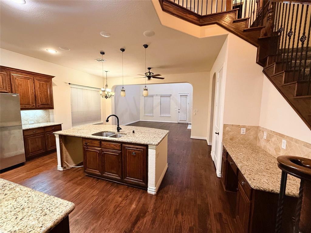 2215 Longview Road Irving, TX 75063 - Photo 3 of 25 Kitchen with a central island featuring a double-basin sink, granite countertops, wood-finish flooring, and recessed lighting