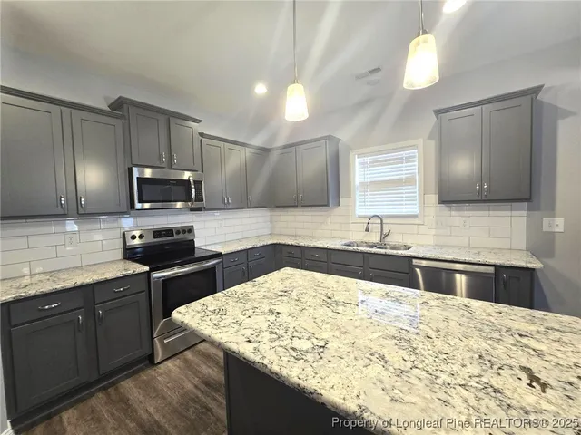 a kitchen with stainless steel appliances kitchen island granite countertop a sink stove and refrigerator