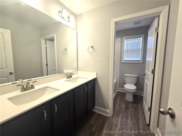 a bathroom with a double vanity sink toilet and a mirror