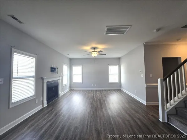 an empty room with wooden floor chandelier and windows