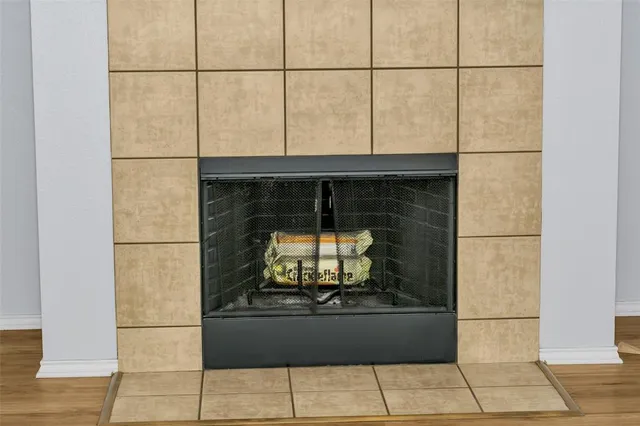 a view of an empty room with wooden floor fireplace and a window