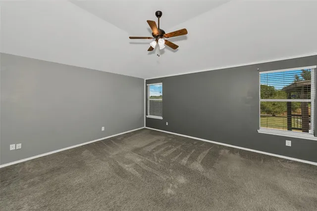 an empty room with windows and fan