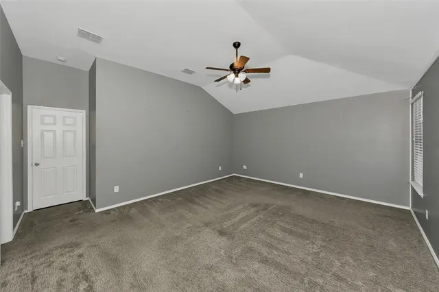 an empty room with ceiling fan and window