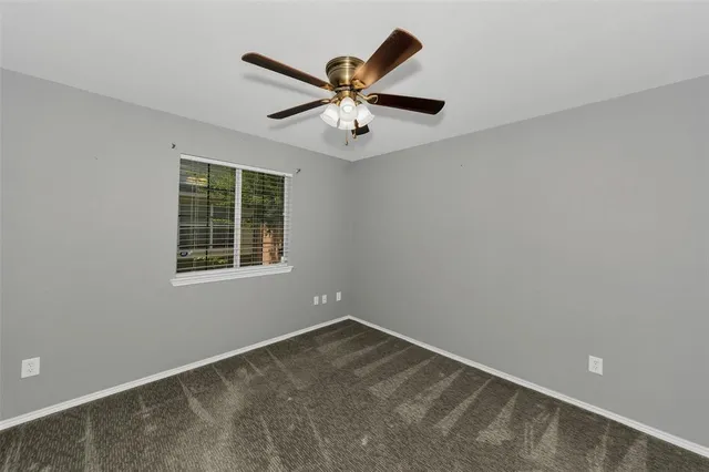 an empty room with ceiling fan and windows