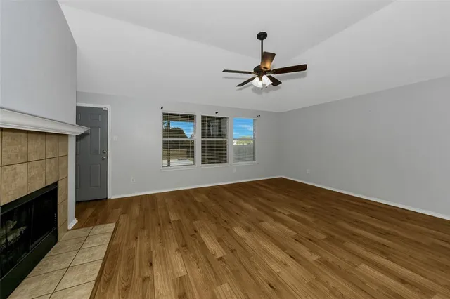 a view of empty room with wooden floor and window