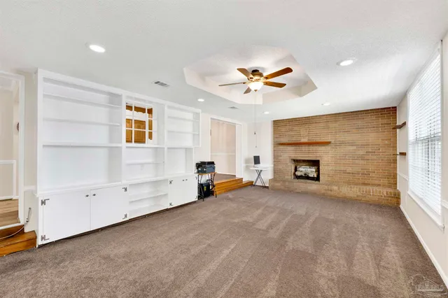 an empty room with windows and fireplace