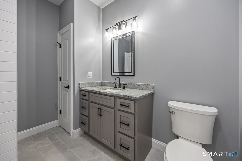 210 Munson Road, Unit 2G Wolcott, CT 06716 - Photo 20 of 23 a bathroom with a granite countertop toilet a sink and a mirror