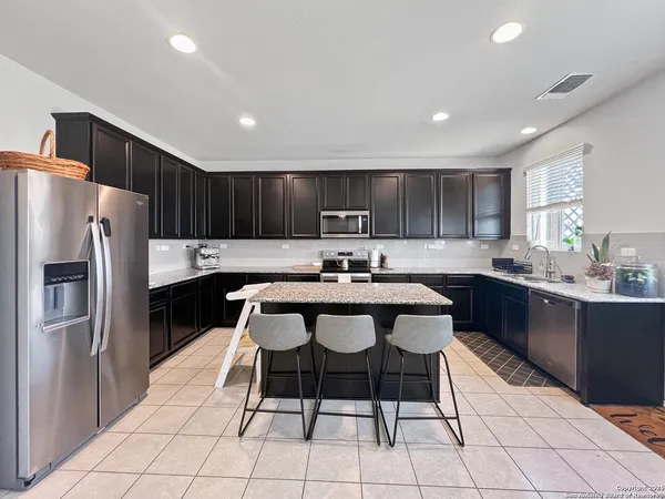 a kitchen with granite countertop a center island a counter space stainless steel appliances and cabinets
