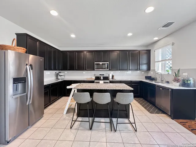 a kitchen with granite countertop a center island a counter space stainless steel appliances and cabinets