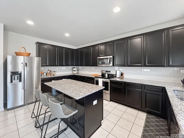 a kitchen with stainless steel appliances granite countertop a table chairs sink refrigerator and cabinets