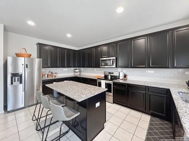 a kitchen with stainless steel appliances granite countertop a table chairs sink refrigerator and cabinets