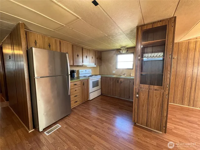 a kitchen with stainless steel appliances a refrigerator and wooden floor