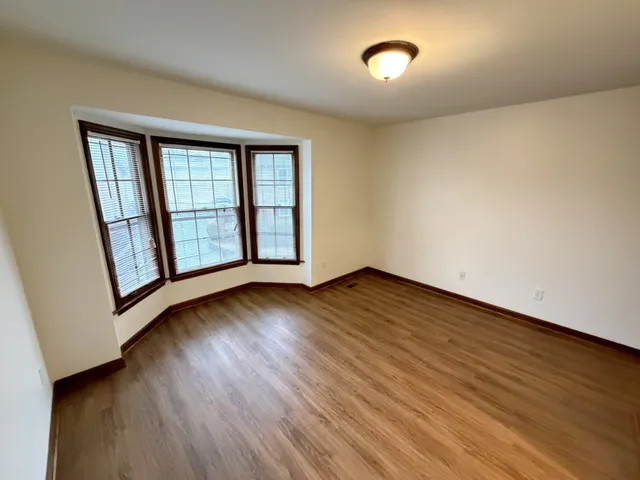 an empty room with wooden floor and mirror