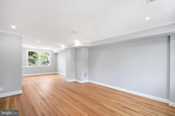 a view of an empty room with wooden floor and window