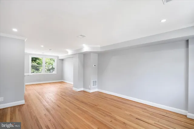 a view of an empty room with wooden floor and window
