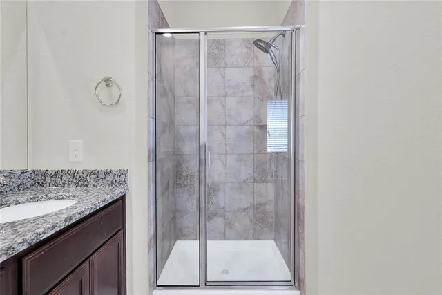 a bathroom with a granite countertop shower sink vanity and mirror