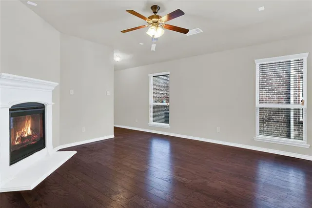 a view of an empty room with window and wooden floor