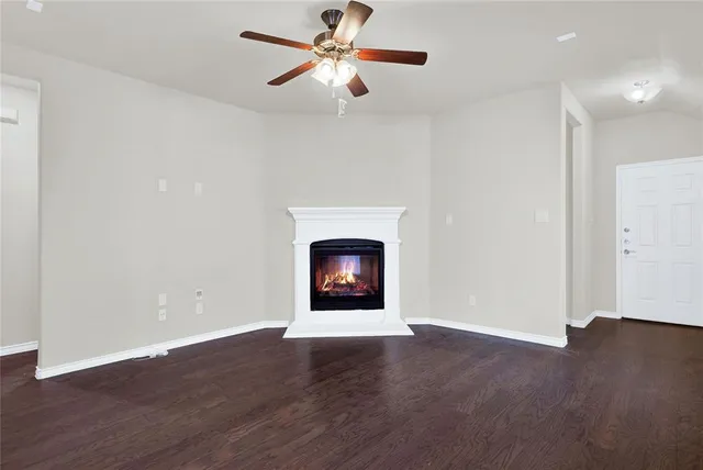 a view of an empty room with wooden floor a fireplace and a window