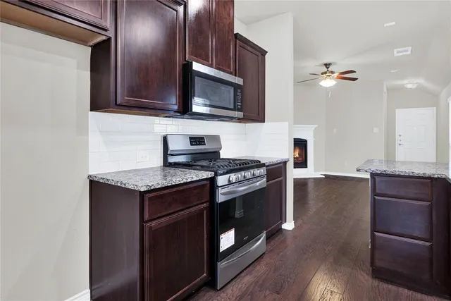 a kitchen with stainless steel appliances granite countertop a stove a microwave and a refrigerator