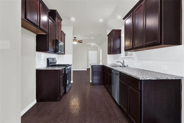 a kitchen with stainless steel appliances granite countertop wooden cabinets a stove top oven a sink and dishwasher
