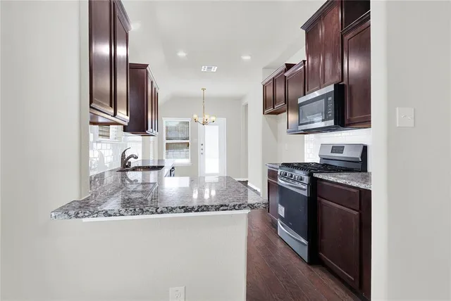 a kitchen with stainless steel appliances granite countertop a sink stove and refrigerator