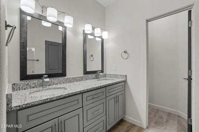 a bathroom with a granite countertop double vanity sink and a mirror