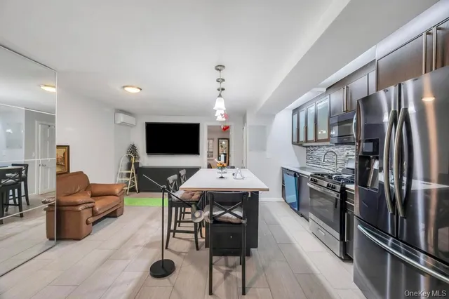 a kitchen with kitchen island a dining table chairs stainless steel appliances and cabinets