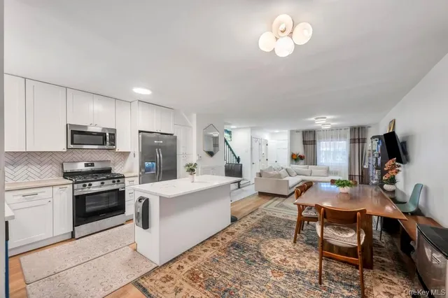 a living room with stainless steel appliances granite countertop furniture a fireplace a flat screen tv and kitchen view