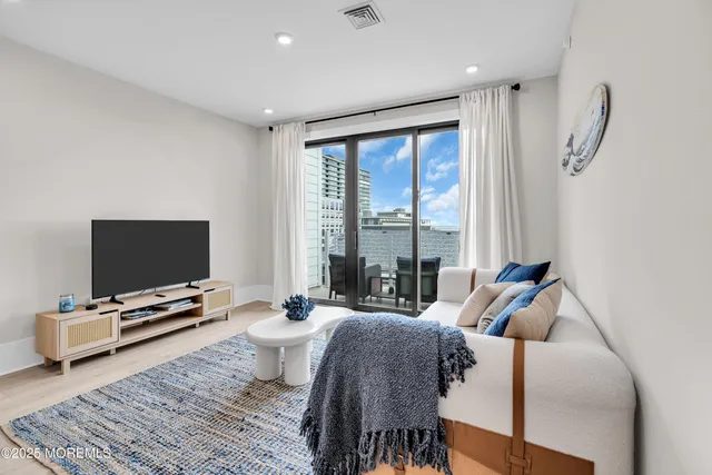 a living room with furniture a flat screen tv and a large window