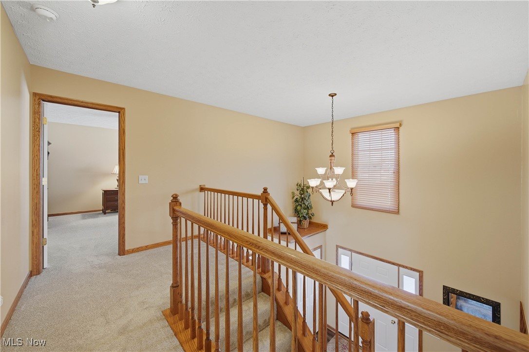 2132 Summerchase Road Northeast Canton, OH 44721 - Photo 20 of 49 Hallway with an upstairs landing, light colored carpet, and a chandelier