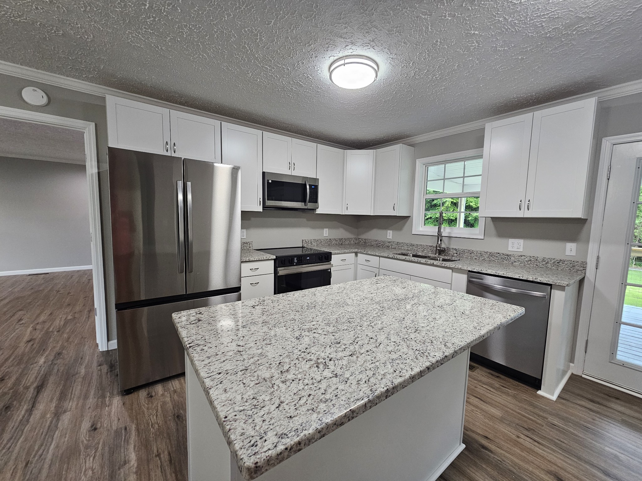 362 Forest Point Road Monteagle, TN 37356 - Photo 25 of 42 a kitchen with granite countertop a refrigerator a sink a stove a microwave and island with wooden floor