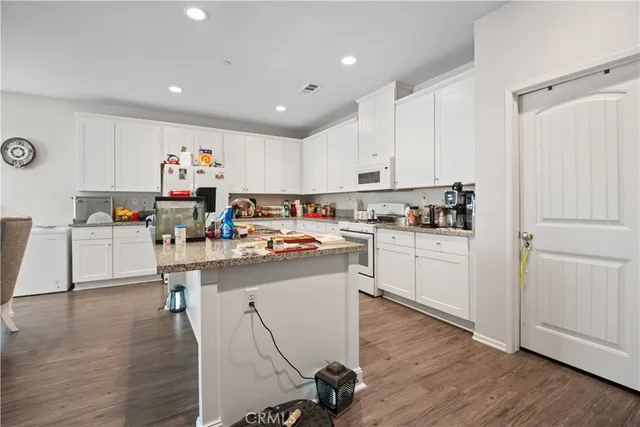 a kitchen that has a lot of white cabinets and wooden floor