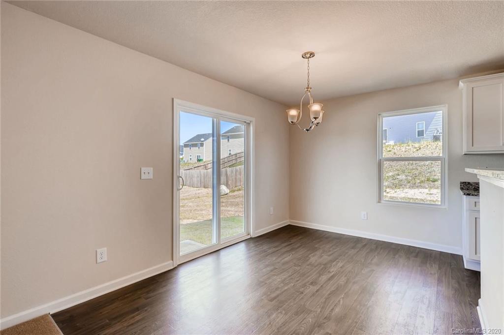 3421 Ellingford Road Charlotte, NC 28214 - Photo 8 of 16 an empty room with wooden floor chandelier and windows