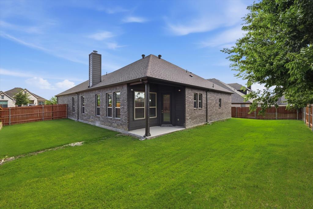 4017 Alpine Street Midlothian, TX 76065 - Photo 34 of 37 Expansive backyard featuring a covered patio, brick exterior, multiple windows, a prominent chimney, and a privacy fence
