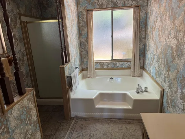 a bathroom with a tub a sink and a large mirror