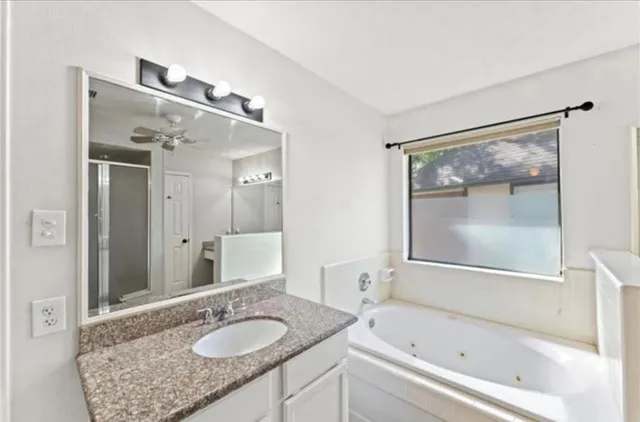 a bathroom with a granite countertop tub sink and mirror