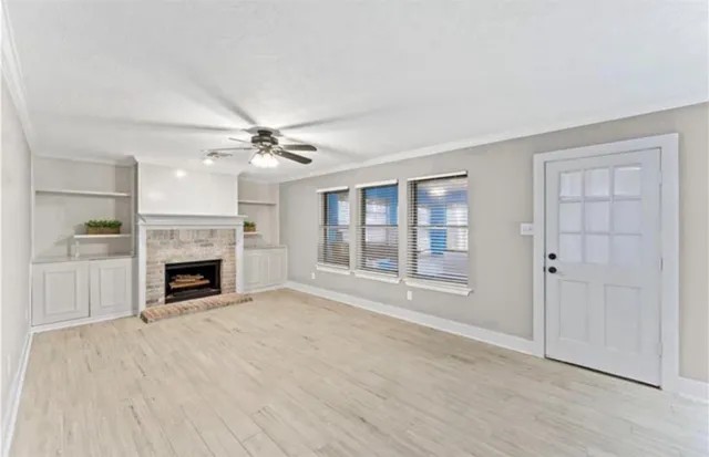 a view of a livingroom with a fireplace a ceiling fan and windows