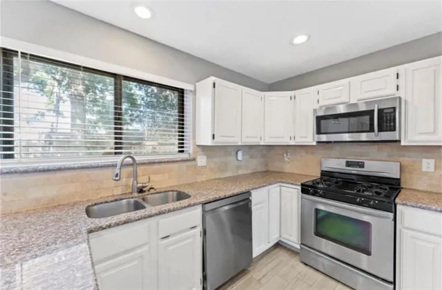 a kitchen with granite countertop a sink stainless steel appliances and cabinets