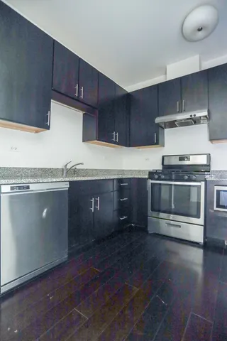 a kitchen with granite countertop a stove a cabinets and wooden floor