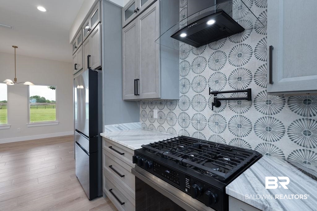13066 Gopher Court Elberta, AL 36530 - Photo 7 of 38 Modern kitchen featuring a patterned backsplash, stainless steel appliances, light gray cabinetry, and wood-finish flooring.