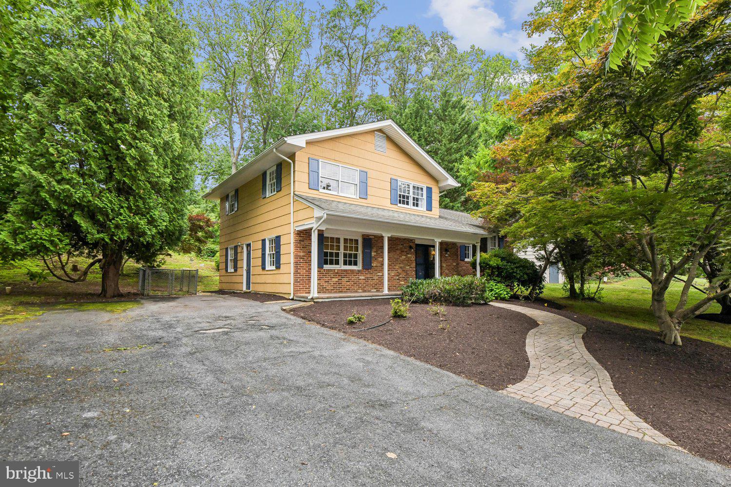 a front view of a house with a garden and trees