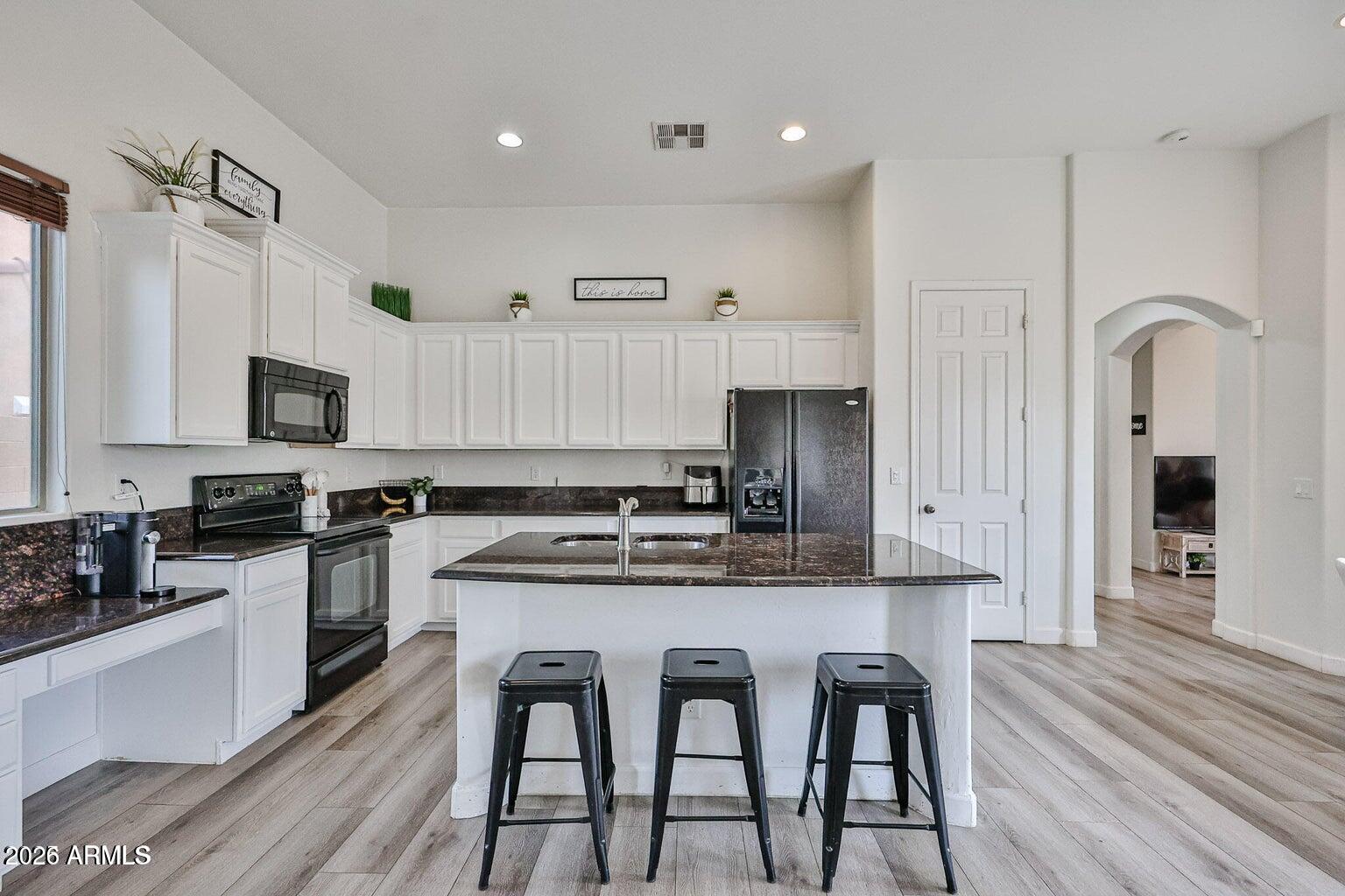 3950 North Edith Way Buckeye, AZ 85396 - Photo 9 of 32 a kitchen with stainless steel appliances granite countertop a white cabinets and wooden floor