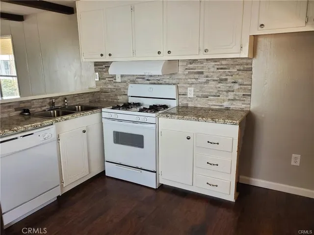 a kitchen with granite countertop white cabinets and white appliances