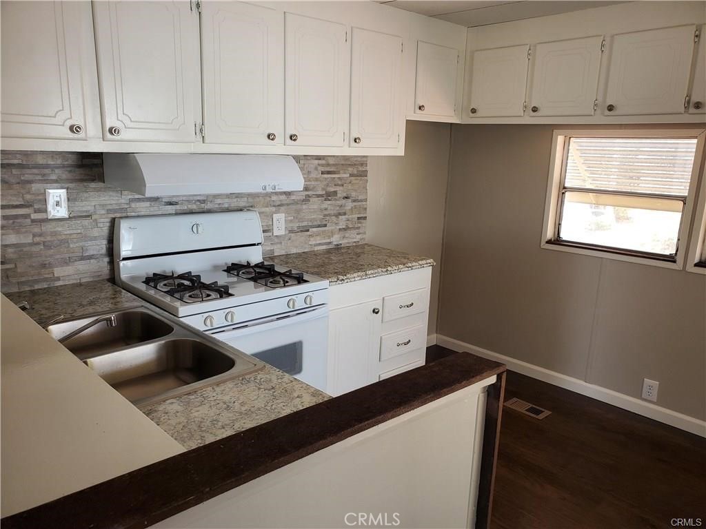 2240 Golden Oak Lane, Unit 132 Merced, CA 95341 - Photo 6 of 13 a kitchen with granite countertop a sink dishwasher a stove and white cabinets