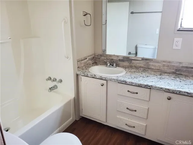 a bathroom with a granite countertop sink toilet and bathtub
