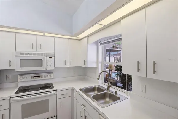 a kitchen with white cabinets sink and appliances