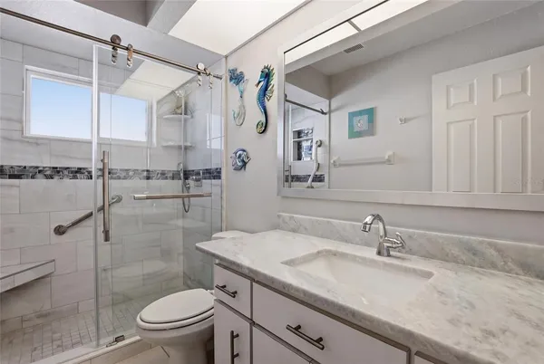 a bathroom with a granite countertop sink toilet and shower