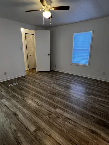 an empty room with wooden floor closet and a ceiling fan